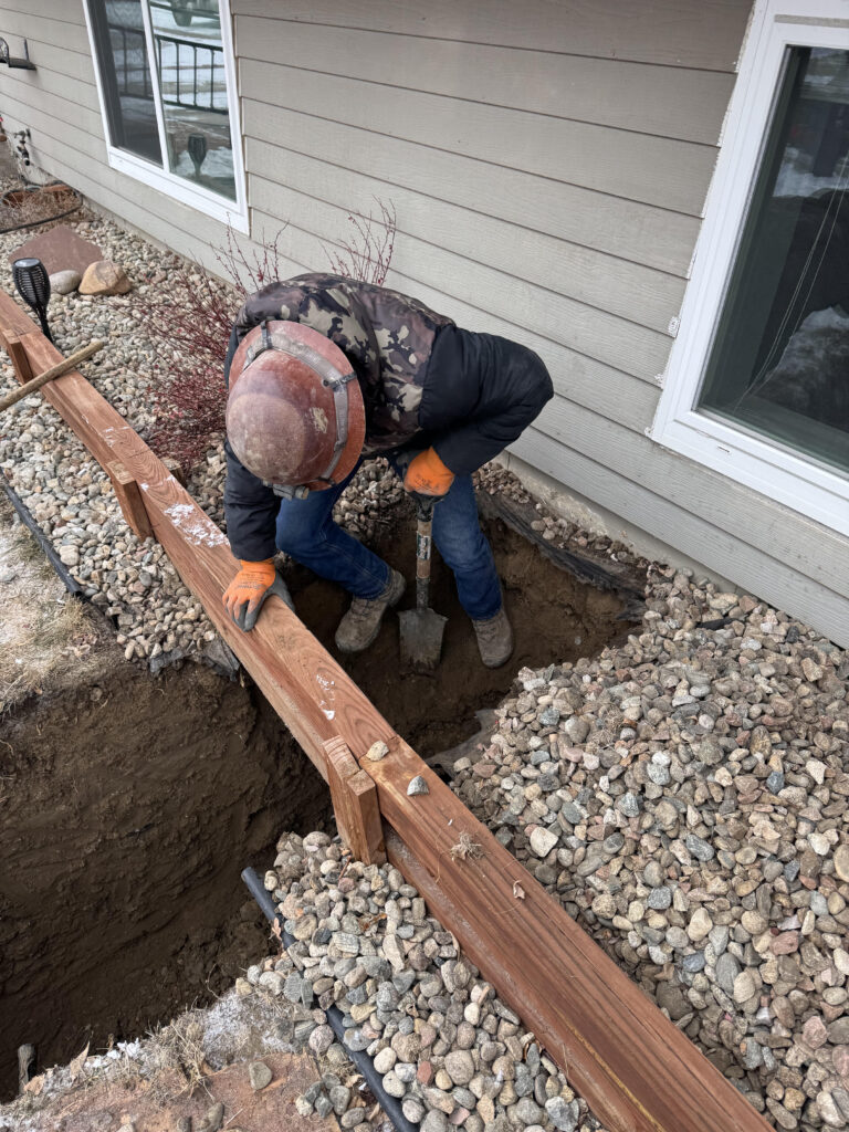 Gabriel digging a small access excavation along the foundation for a trenchless sewer line repair
