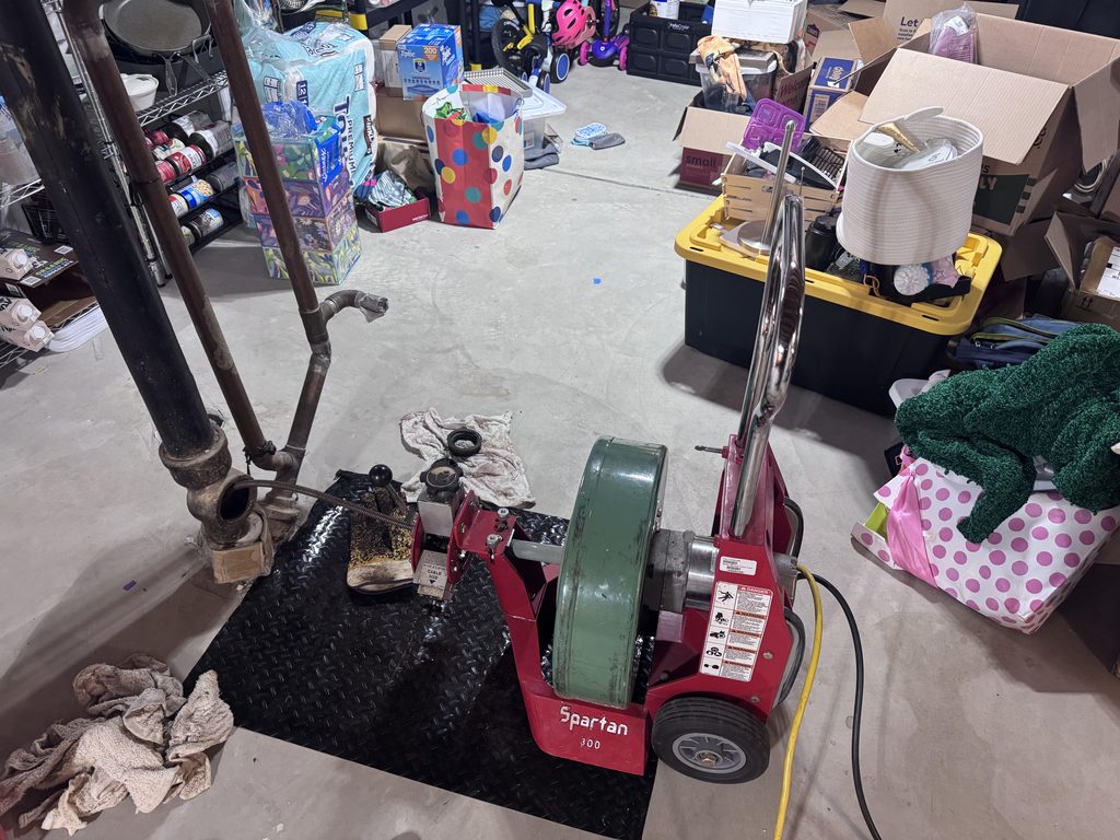 Professional drain snaking service clearing clogged drain with rooter equipment