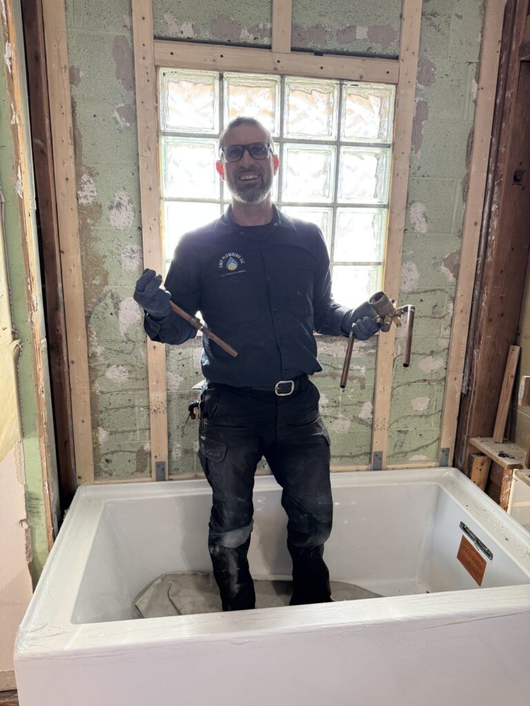 GMP Plumbing plumber holding an old shower valve removed during a bathtub and shower valve replacement